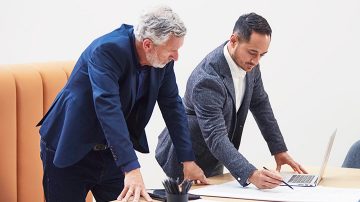 Two male colleagues discussing work over a laptop